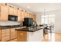 Bright kitchen with light wood cabinets, a black refrigerator, and stainless steel appliances at 13664 Cherry St, Thornton, CO 80602