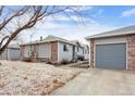 Exterior view of a house with a gray garage door, brick accents, and tidy landscaping at 2027 Terry St # 1, Longmont, CO 80501