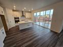 Modern kitchen with white cabinetry, stainless steel appliances, and a large island with hardwood floor at 7279 Prairie Sage Pl, Littleton, CO 80125