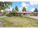 Lovely single-story home with a lush front lawn, mature trees and stone landscape accents at 10525 W 18Th Ave, Lakewood, CO 80215
