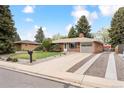 A charming single-story brick home featuring a well-kept front lawn with mature trees at 10525 W 18Th Ave, Lakewood, CO 80215