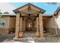 Inviting front entrance featuring stone columns, a wooden door, decorative planters, and a flagstone landing at 5329 Pinyon Jay Rd, Parker, CO 80134