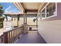 Covered porch with wood decking, railing, decorative stone pillars, and partial view of backyard at 7370 S Catawba Way, Aurora, CO 80016