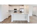 Bright kitchen features white cabinets, stainless appliances, and a large center island at 587 Nightsky St, Erie, CO 80516