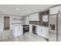 Modern kitchen featuring stainless steel appliances, white cabinets, and a stylish black and white backsplash at 6880 Pontiac St, Commerce City, CO 80022