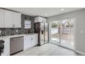 Well-lit kitchen featuring stainless steel appliances, elegant backsplash, and a sliding glass door to the backyard at 6880 Pontiac St, Commerce City, CO 80022