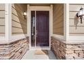 Inviting entryway features a rich wood door framed by stone accents and classic exterior lighting at 12677 Fisher Dr, Englewood, CO 80112