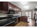 Bright kitchen featuring hardwood flooring, dark wood cabinetry, black appliances, and sliding glass door to backyard at 8893 W Harvard Dr, Lakewood, CO 80227