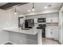 Well-lit kitchen with black appliances, white cabinetry, and a convenient peninsula island at 4899 S Dudley St # 14F, Littleton, CO 80123