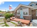 Charming stone house with a blue door and a wooden porch surrounded by green plants and an American flag at 895 Nile Ct, Golden, CO 80401