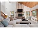 Bright living room with a vaulted wood ceiling, brick fireplace, and views of the surrounding landscape at 2386 Daisy Ln, Golden, CO 80401