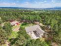 Breathtaking aerial view of a home surrounded by a lush forest and distant mountain views at 20125 Indi Dr, Monument, CO 80132