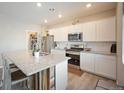 Modern kitchen with white cabinets, granite island, and stainless steel appliances at 27129 E Cedar Ave, Aurora, CO 80018