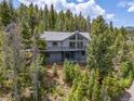 Stunning mountain home exterior with wrap around deck nestled among the trees for a private setting at 6882 Snowshoe Trl, Evergreen, CO 80439