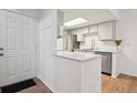 Bright kitchen with white cabinets, stainless steel appliances, breakfast bar, and hardwood floors at 921 S Zeno Way # 201, Aurora, CO 80017