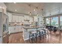 Well-lit kitchen features white cabinets, stainless appliances, hardwood floors, and a breakfast bar with pendant lighting at 23957 E Rocky Top Ave, Aurora, CO 80016