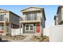 Charming two-story home with a balcony and a red front door is framed by a white picket fence at 5035 N Walden Way, Denver, CO 80249