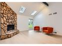 Bright living room featuring a stone fireplace, skylights, and vaulted ceilings at 10295 E Evans Ave # 114, Aurora, CO 80247