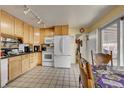 Functional kitchen featuring light wood cabinets, white appliances, and tile flooring at 2551 S Carson Way, Aurora, CO 80014