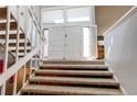 Carpeted staircase leading to a bright two-story foyer with grand double doors, an open concept design at 11651 E Yale Way, Aurora, CO 80014