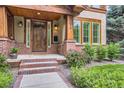 Close-up of a home's front entrance with a striking wood door, brick pillars, and well-maintained landscaping at 1410 S Elizabeth St, Denver, CO 80210