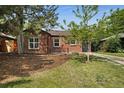 Quaint brick home featuring mature trees in the front yard, complemented by a dark roof and garage at 1111 Kearney St, Denver, CO 80220