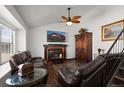 Cozy living room with a brick fireplace, ceiling fan, and hardwood floors, creating a warm and inviting space at 8571 S Estes St, Littleton, CO 80128