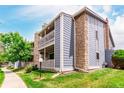 Condo building with stone accents, a covered porch, and well-maintained landscaping on a sunny day at 8335 Fairmount Dr # 10-208, Denver, CO 80247