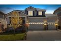 A warm and inviting two-story home at dusk, featuring a three-car garage and a well-manicured lawn at 2208 Bellavista St, Castle Rock, CO 80109
