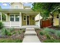 Inviting covered front porch with white railing and lush landscaping leading to the entrance at 2648 Florence St, Denver, CO 80238