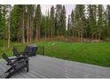 View of a deck with outdoor seating and a grill, surrounded by lush greenery and tall pine trees at 563 Cr 672, Breckenridge, CO 80424
