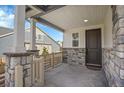 Inviting front porch with stone columns and charming entrance at 10912 Memphis Ct, Commerce City, CO 80022