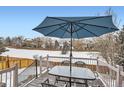 Outdoor deck with table, umbrella, and seating overlooking a snow covered common area at 6366 Nassau Ct, Highlands Ranch, CO 80130