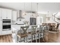 Well-lit kitchen boasts white cabinetry, stainless steel appliances, a large island, and seating for four at 7678 S Old Hammer Way, Aurora, CO 80016