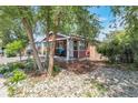 Charming home nestled among mature trees, with inviting front porch and landscaped yard with rock details at 358 S Osceola St, Denver, CO 80219