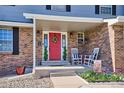 Inviting covered front porch with rocking chairs and red door featuring a wreath and stylish decorations at 7822 W Ottawa Pl, Littleton, CO 80128