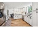 Bright kitchen with white cabinets, stainless steel appliances, hardwood floors and black hardware throughout at 7822 W Ottawa Pl, Littleton, CO 80128