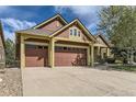 A view of the home highlighting the three car garage and brown and tan color scheme at 1562 Suncrest Rd, Castle Rock, CO 80104