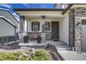 Inviting covered porch with stone pillars, seating, and stylish planters at 5392 Sanctuary Ave, Firestone, CO 80504