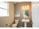 Bright powder room with pedestal sink, oval mirror, modern light fixture and neutral paint at 15858 E Broncos Pl, Englewood, CO 80112