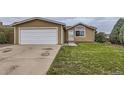 Single-story home with attached garage, complemented by a lush, green front yard at 664 Stampede Dr, Brighton, CO 80603
