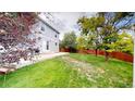 Lush backyard featuring a well-maintained lawn, mature trees, and a concrete patio, ideal for outdoor gatherings at 2160 Ance St, Strasburg, CO 80136