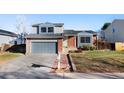 Inviting two-story home with a gray garage door, brick details, and a lovely walkway to the entrance at 19697 E Flora Pl, Aurora, CO 80013