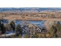 Aerial view of home with water view, natural landscape, bare trees, and mountains in the distance at 10667 E Goose Haven Dr, Lafayette, CO 80026