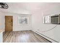 Bright living room featuring modern vinyl floors, a unique glass block window, and neutral wall color at 1265 Colorado Blvd # 12, Denver, CO 80206