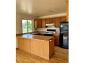 A kitchen featuring wood cabinets, black appliances, and an island at 11318 Clermont Dr, Thornton, CO 80233