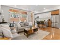 Bright living room with hardwood floors, a grey sofa, and a modern kitchen view at 2640 Central Ct # 104, Denver, CO 80211