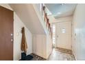 The entryway features wood-look tile flooring, white walls, coat rack, and stairwell access at 2695 S Ames Way # 1, Lakewood, CO 80227