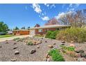 Brick home with gravel landscaping, mature shrubs and adjacent garage viewed on a sunny day at 6105 Benton St, Arvada, CO 80003