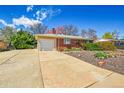 Exterior view of house with attached garage, landscaped front and large driveway for multiple car parking at 6105 Benton St, Arvada, CO 80003
